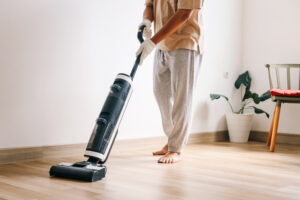 Cropped image of a person vacuuming a living room rug.